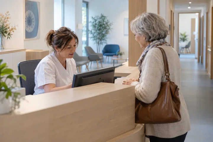 À l’accueil d’un centre d’ophtalmologie, une secrétaire enregistre l’arrivée d’une patiente